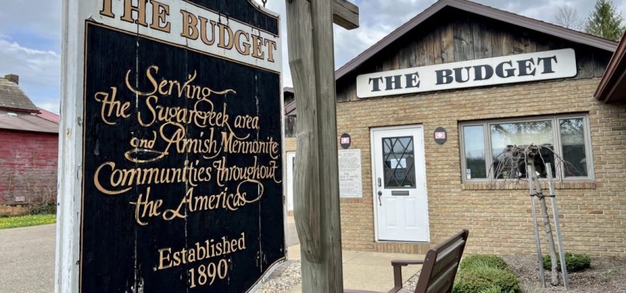 The Budget's brick building and wooden sign as seen from outside.
