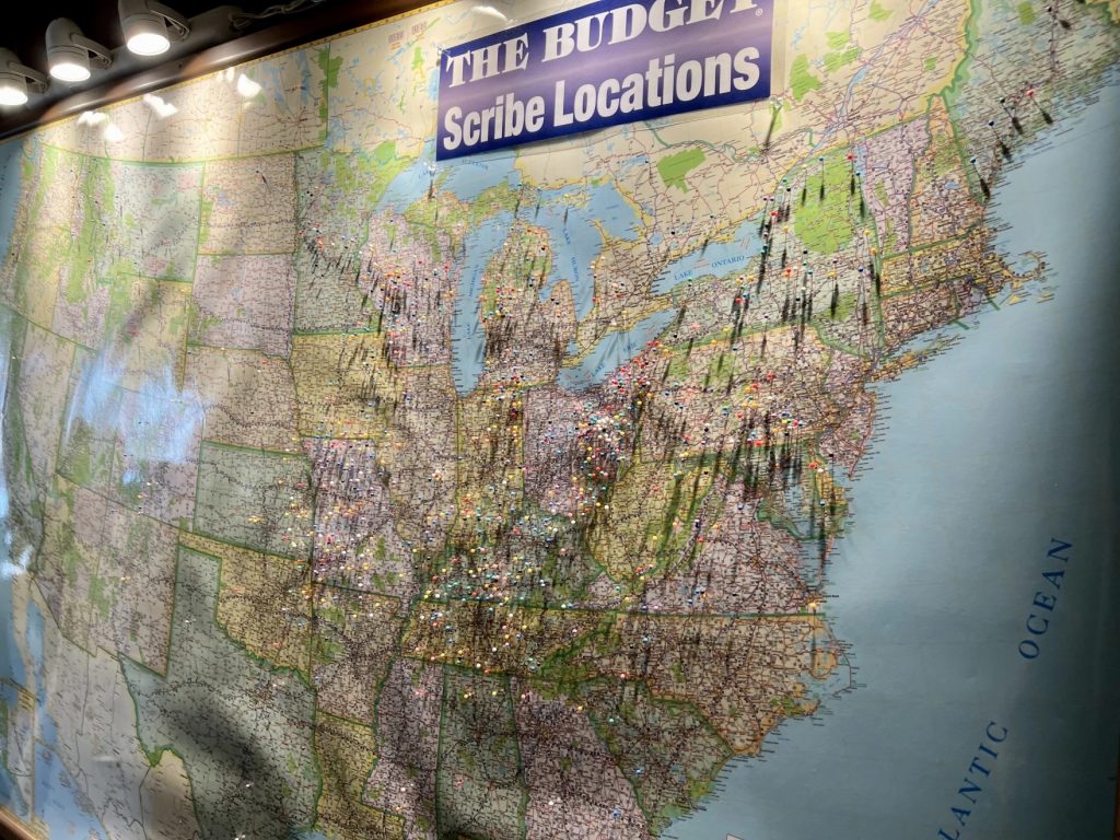 Pins on a large map in The Budget office mark the cities that Amish scribes write in from.