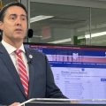 Ohio Secretary of State Frank LaRose speaks at a podium with a screen with data behind him.