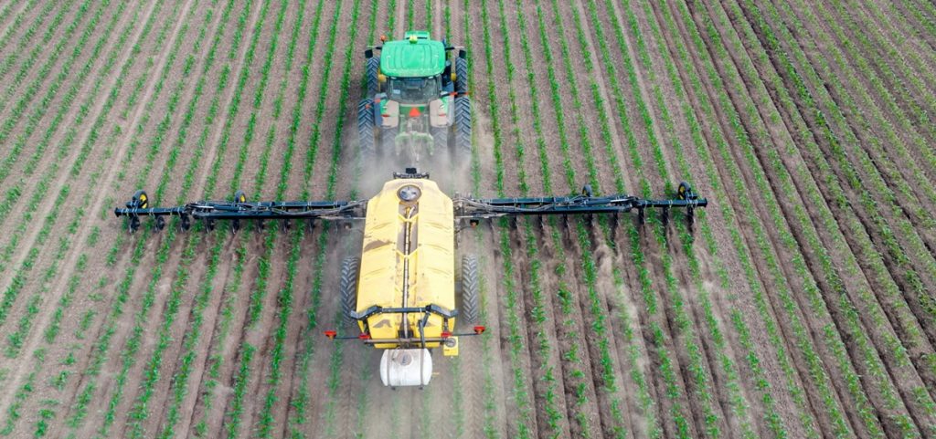 A large piece of farming equipment rolls over a field.