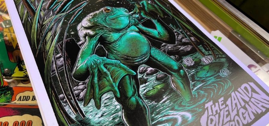 A poster created by eastonhawkillustration of the Loveland Frogman in Brian Maxson's barbershop shows the creature standing in a river.