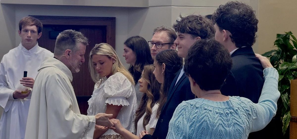 Fr. Robert Jones holds the hands of a student at the University of Dayton after anointing her for confirmation