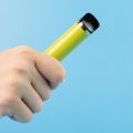 disposable vape in smoker's hand on blue background
