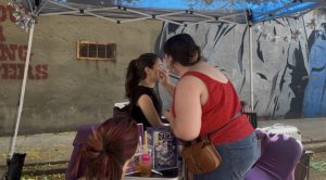 Face painter Tiffany Davis paints a design on a young attendee's face during Boogie on the Bricks in Athens.