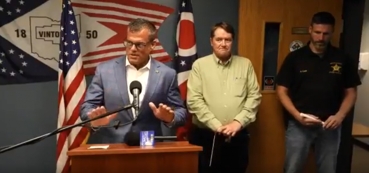 Ohio Attorney General Andy Wilson speaks at a podium during a press conference with Vinton County Prosecutor William Archer and Vinton County Sheriff Ryan Cain.