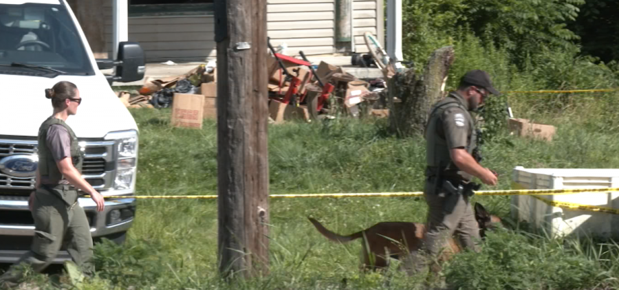 Investigators search the outside of a home in Vinton County where 16 children sharing a single room were removed on Tuesday.