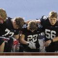 Coal Grove players huddle and take a knee before a high school football game.