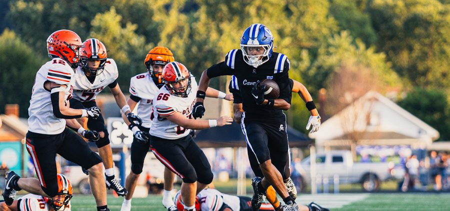 Cartae Ligon carrying the ball, weaving to get past Wheelersburg players as they try to tackle him.