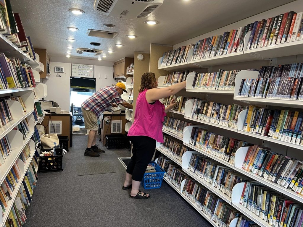 During a lull in activity, two Holmes County librarians shelve returned books onboard the bookmobile.
