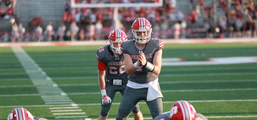 Sheridan is getting to snap the ball to form a play from the quarterback.