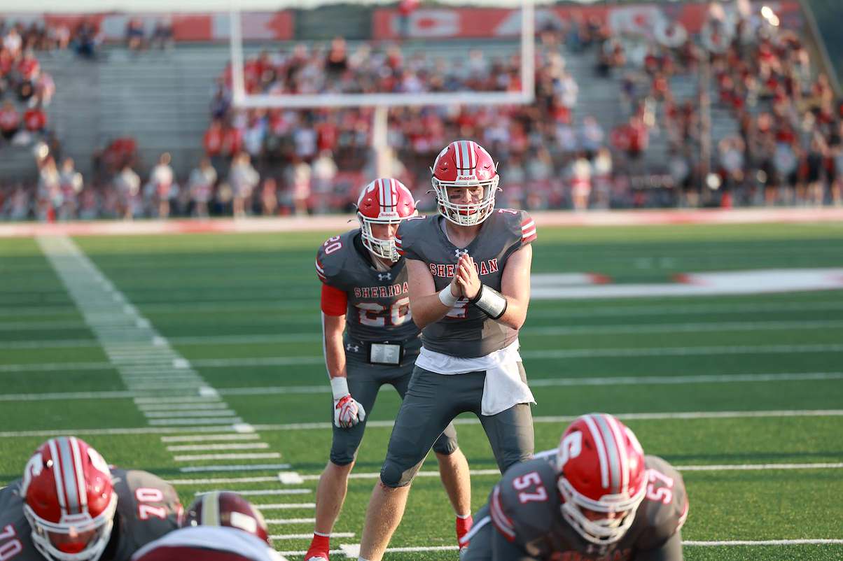 Sheridan is getting to snap the ball to form a play from the quarterback.