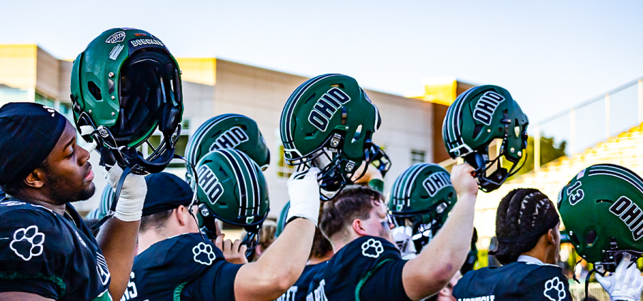 Ohio Football players lifting their helmets in celebration in win against Stonehill