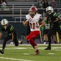 Symmes Valley player is running with the ball away from Green players to try and gain yards.