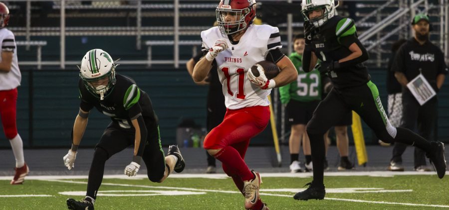 Symmes Valley player is running with the ball away from Green players to try and gain yards.