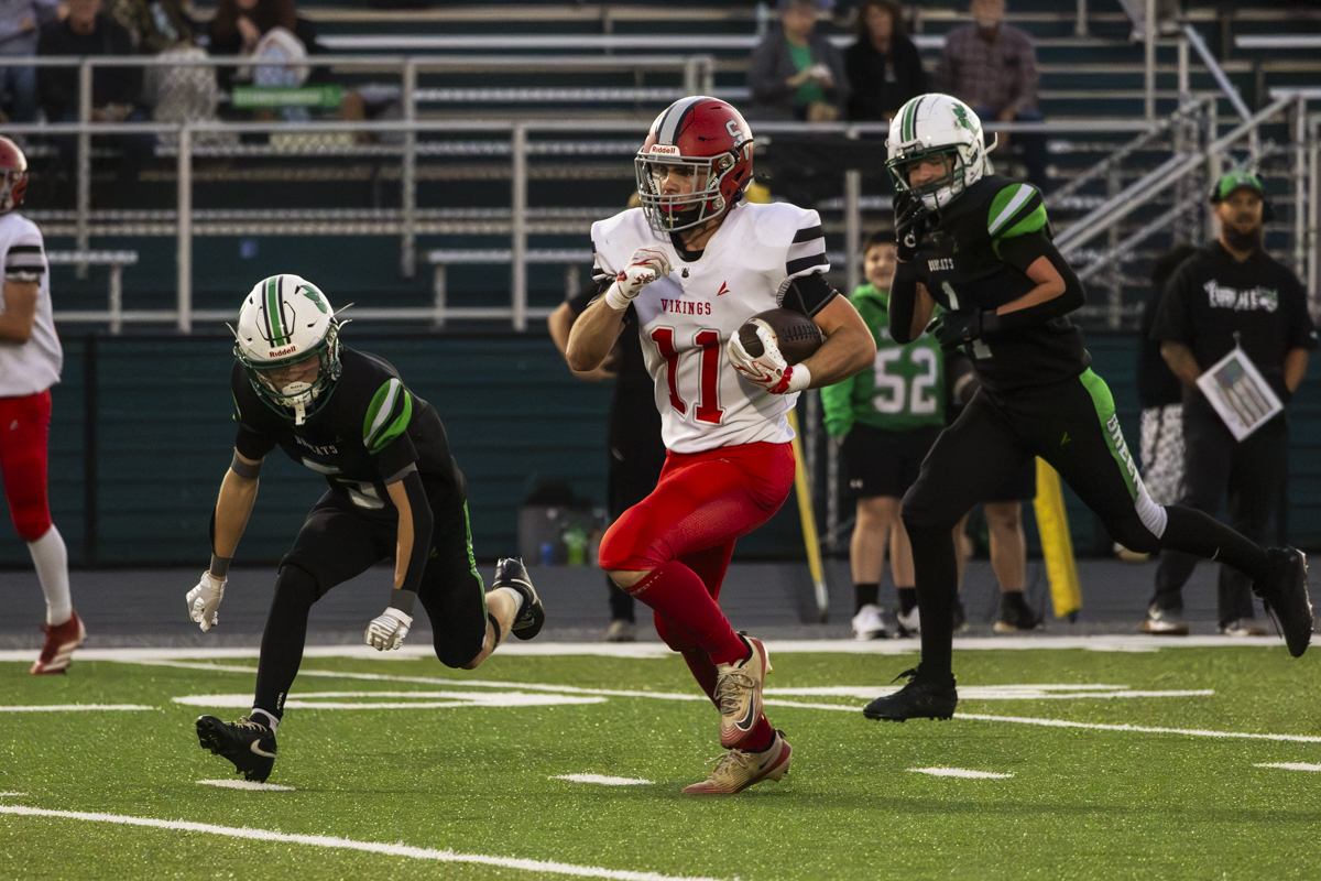 Symmes Valley player is running with the ball away from Green players to try and gain yards.