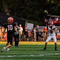 A Wheelersburg Pirate's player is running to a Jackson Ironman player while he is trying to catch the ball.