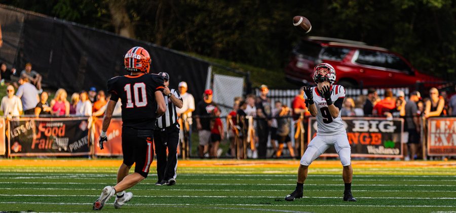 A Wheelersburg Pirate's player is running to a Jackson Ironman player while he is trying to catch the ball.