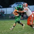 A Nelsonville-York athlete is trying to tackle a Waterford athlete who is running with the ball.