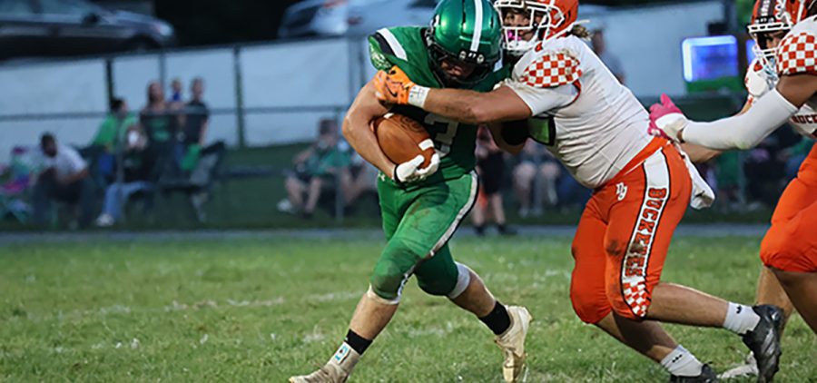 A Nelsonville-York athlete is trying to tackle a Waterford athlete who is running with the ball.