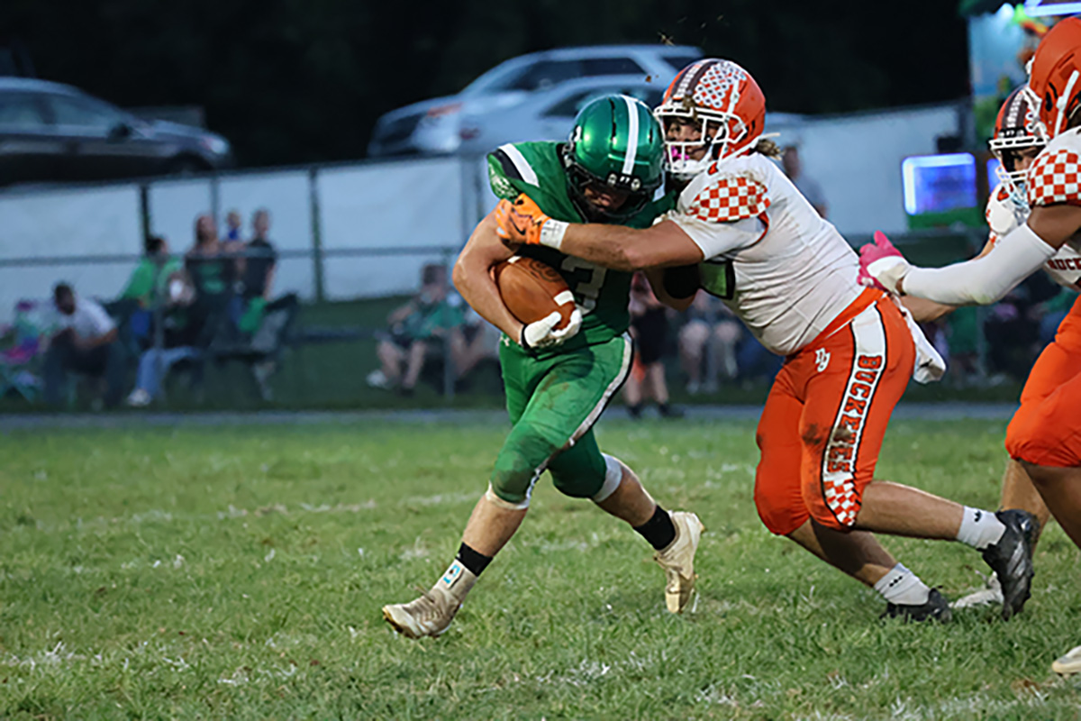 A Nelsonville-York athlete is trying to tackle a Waterford athlete who is running with the ball.