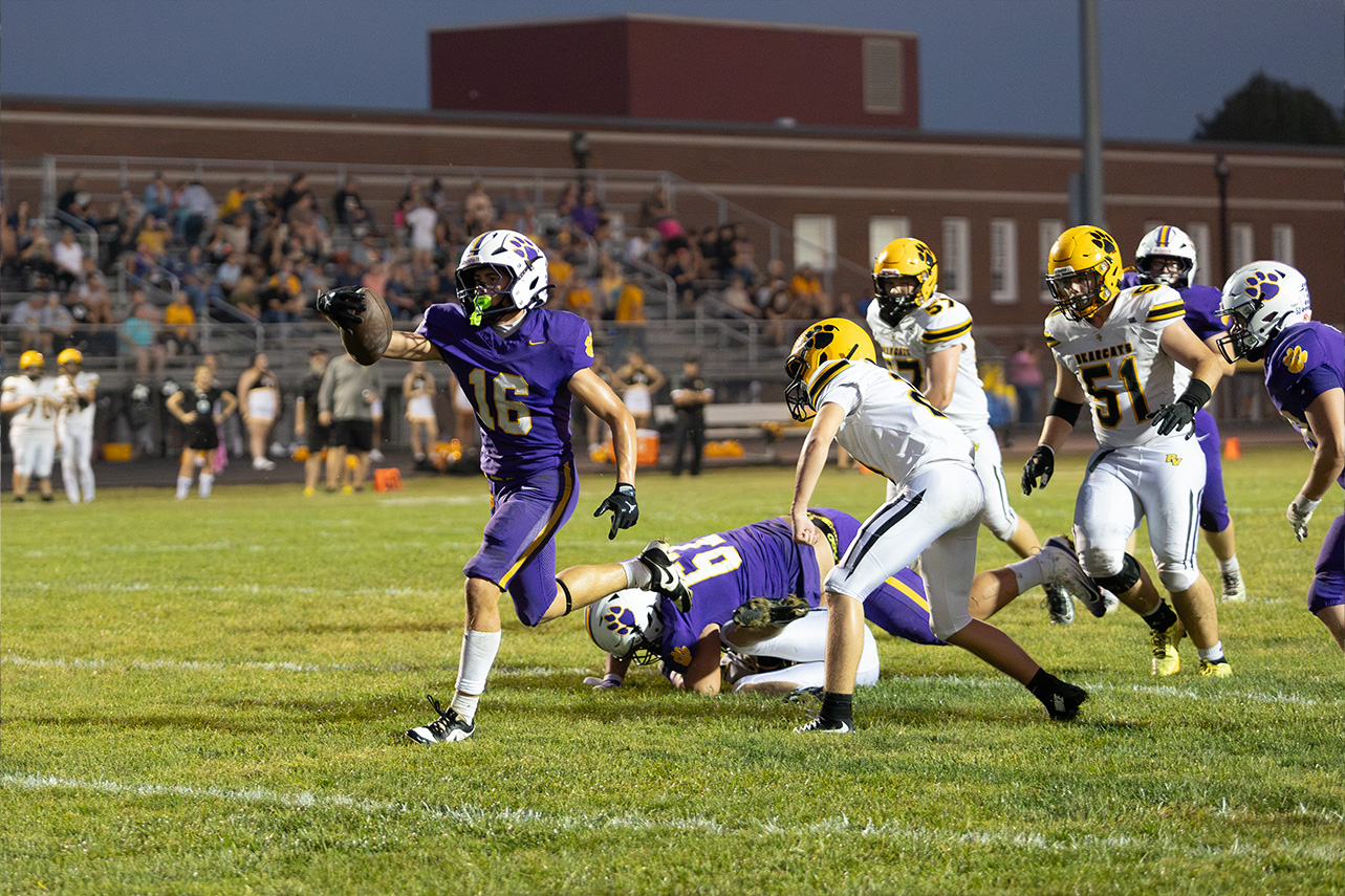 McClain player is running past Paint Valley players to try and reach the end zone.