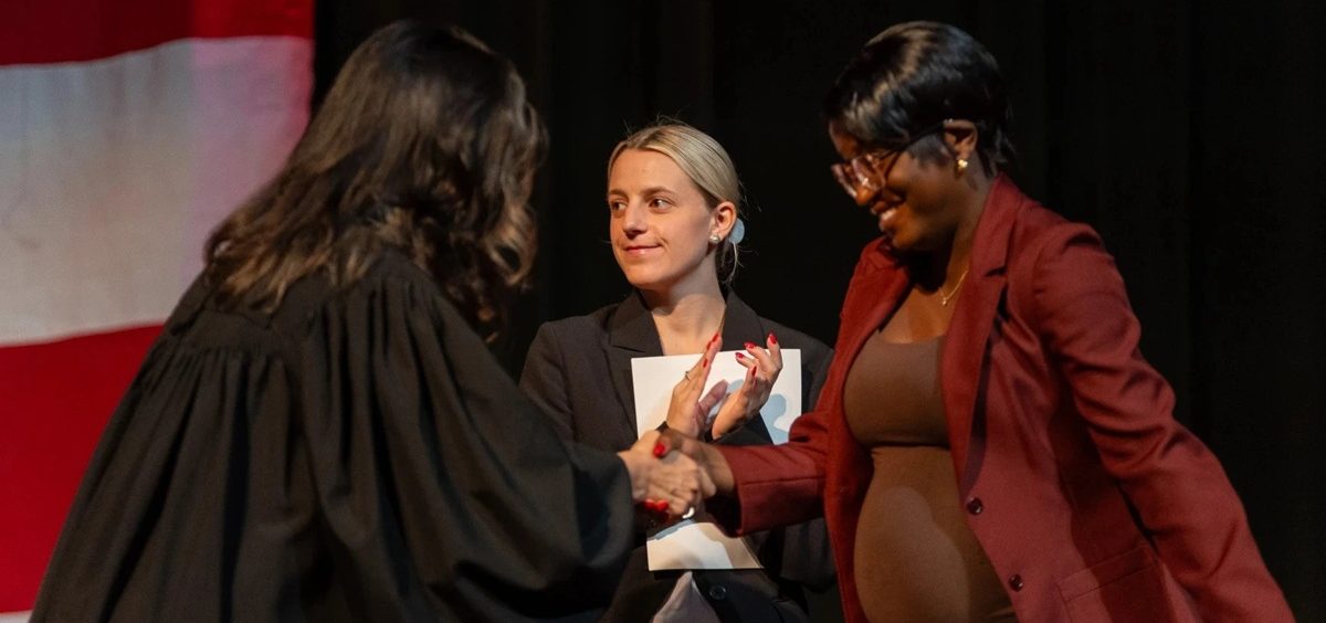 Faith Isaya (right) shakes hands with Judge Suzana Krstevski Koch (left) during her naturalization ceremony in the Brecksville-Broadview Heights High School auditorium.