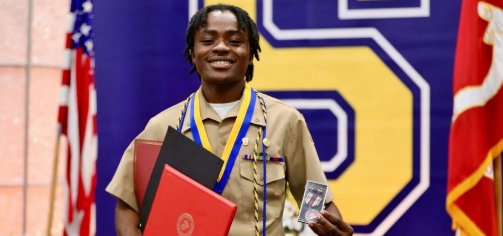 Pierra Damas Bel holds up certificates and a medal at a graduation ceremony.