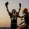 Two Ironton Fighting Tigers are celebrating after a touchdown in the end zone.