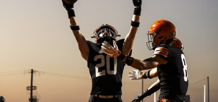 Two Ironton Fighting Tigers are celebrating after a touchdown in the end zone.