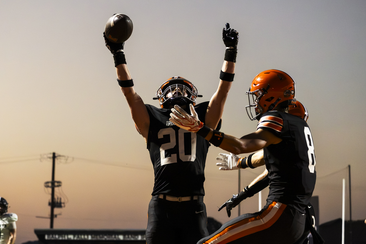 Two Ironton Fighting Tigers are celebrating after a touchdown in the end zone.