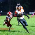 Belpre athlete is running with the ball while a Trimble player is trying to tackle him.