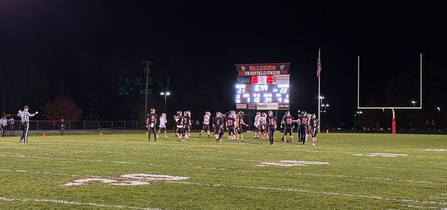 players in black and white jerseys line up on the field.