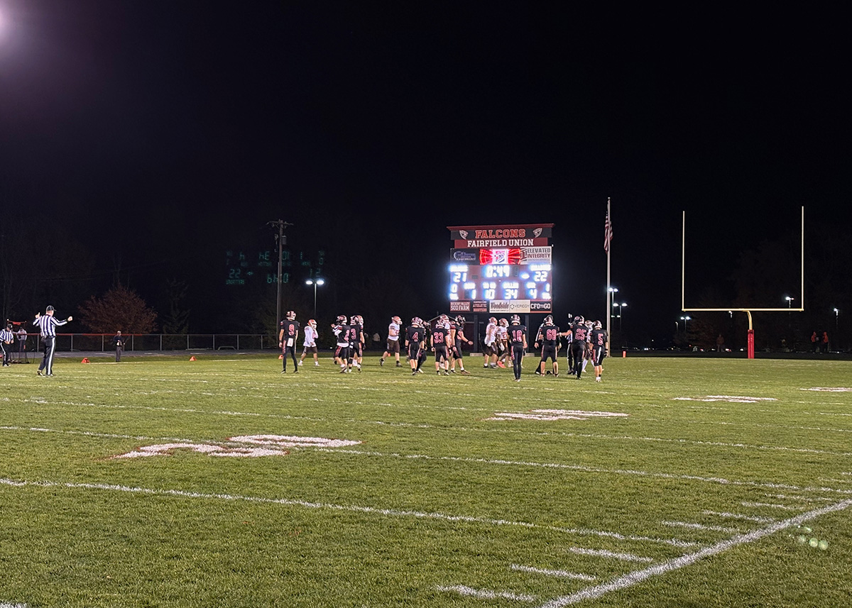 players in black and white jerseys line up on the field.