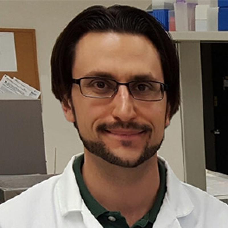 Justin Holub poses for a portrait in a lab coat
