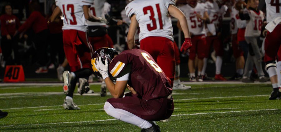 Meigs player kneeling on the field in a maroon jersey