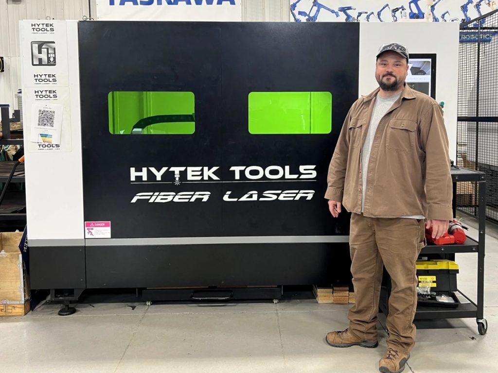 Nate Huddleston stands in front of a Fiber Laser.