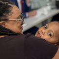 Shemya Wilson holds her son while sitting at a table.
