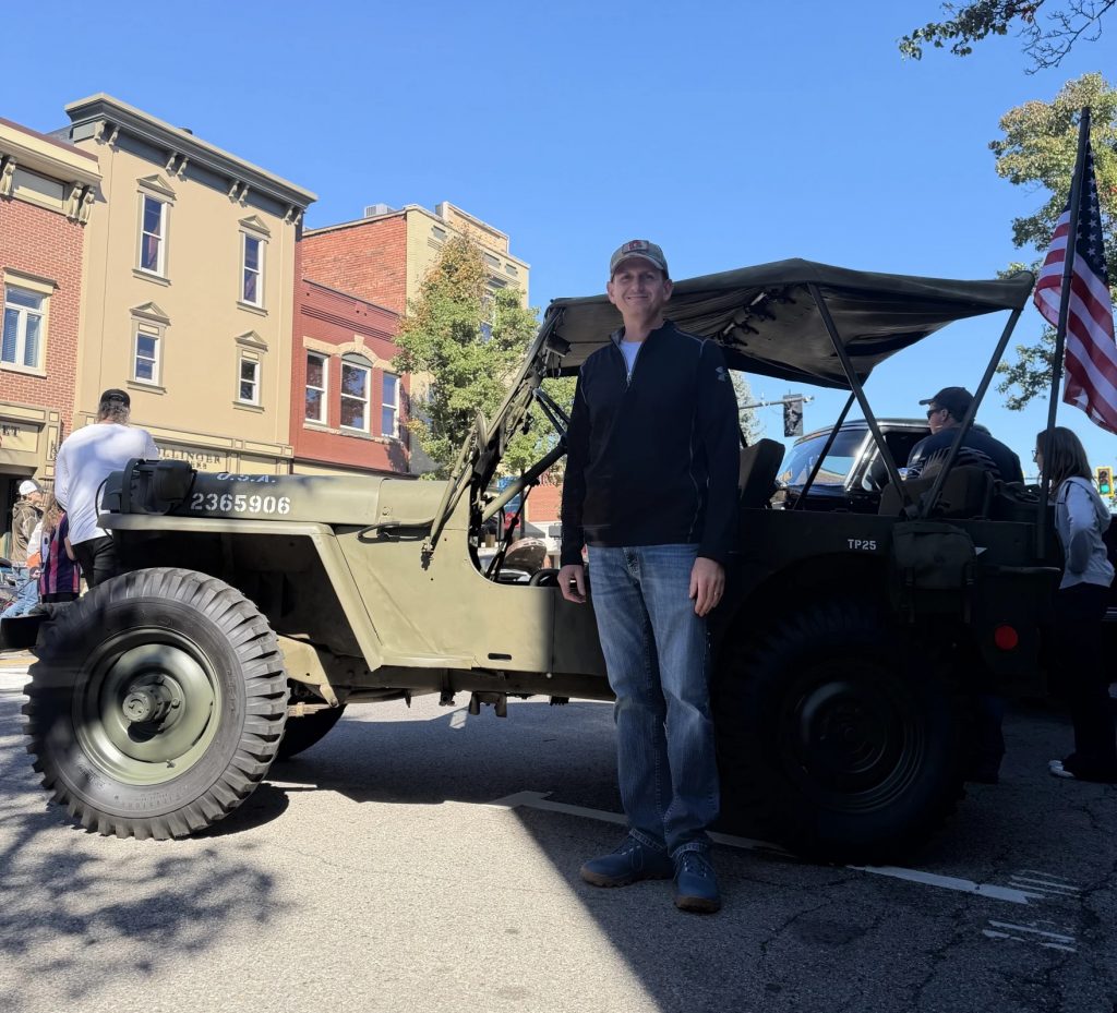 Joshua Clegg stands by his antique Jeep at Woosterfest.